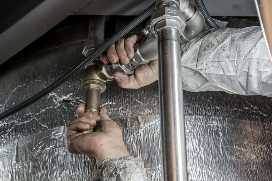 Plumber’s hands installing steel pipes